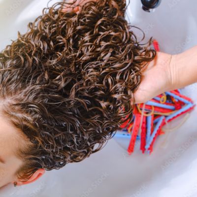 Image d'une femme en train de réaliser une permanente au salon Nuance Coiffure.